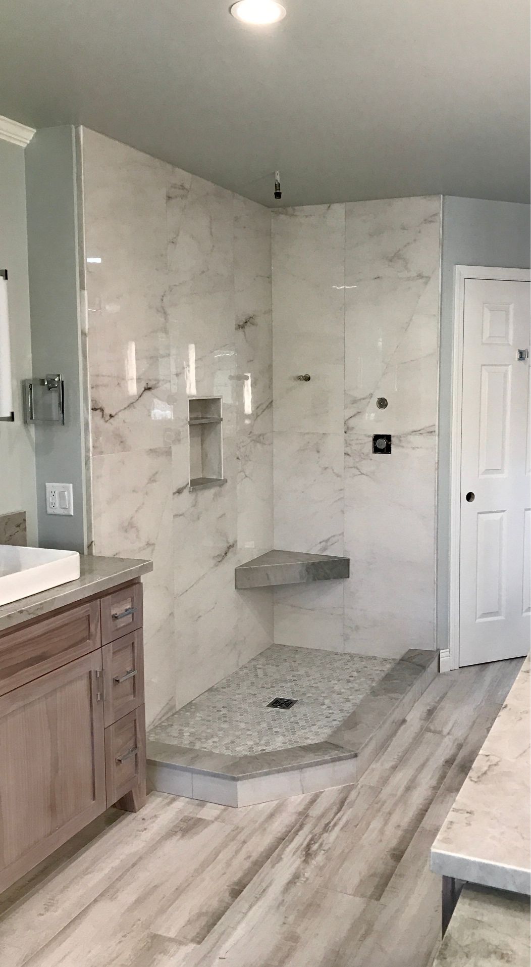 A professional tile installer in San Luis Obispo County, CA installed this gorgeous marble shower with a bench seat. The shower floor has penny mosaic tile in various shades of gray.