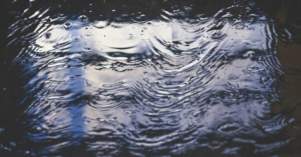 Flooded tile floor. The reflection of a nearby window appears on the surface of the water.