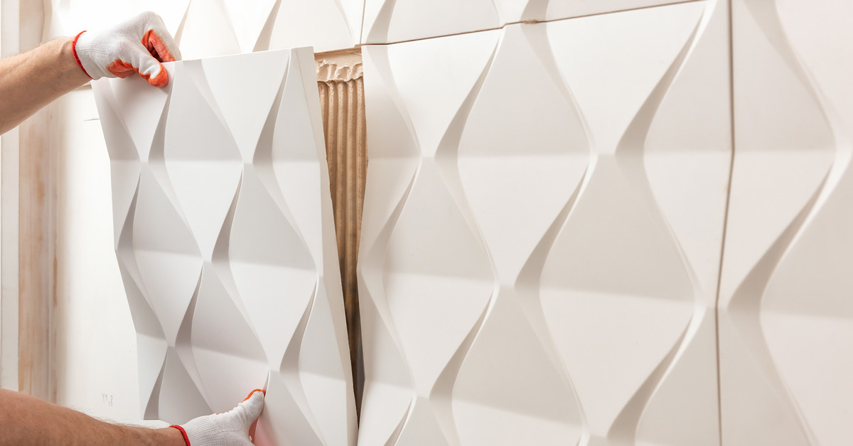 An installer places a 3-D tile on an accent wall.