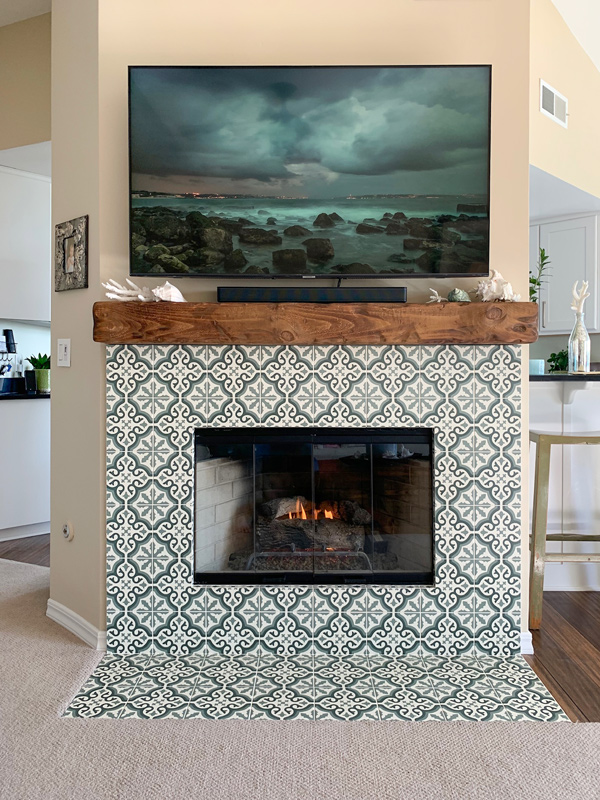 Patterned tile has been beautifully installed around a fireplace. A large flat screen hangs over the fireplace.