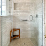 Walk In Shower with Pebble Tile Floor and Herringbone Niche