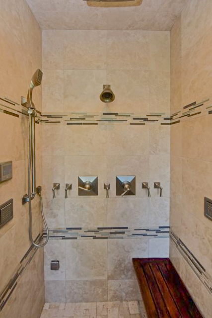 Walk in shower with custom tile design and wood bench