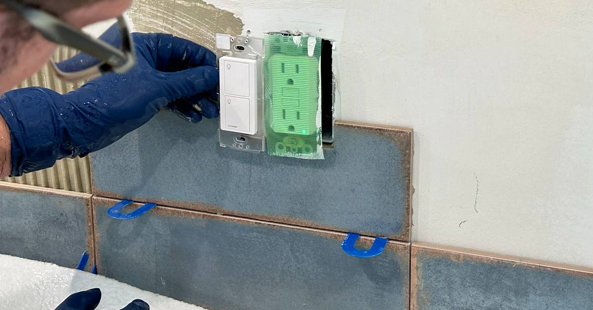This image shows the tile installer working around a wall outlet.