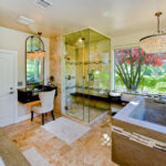 Gorgeous tile and stone bathroom with a shower, tub, vanity, and chandelier.