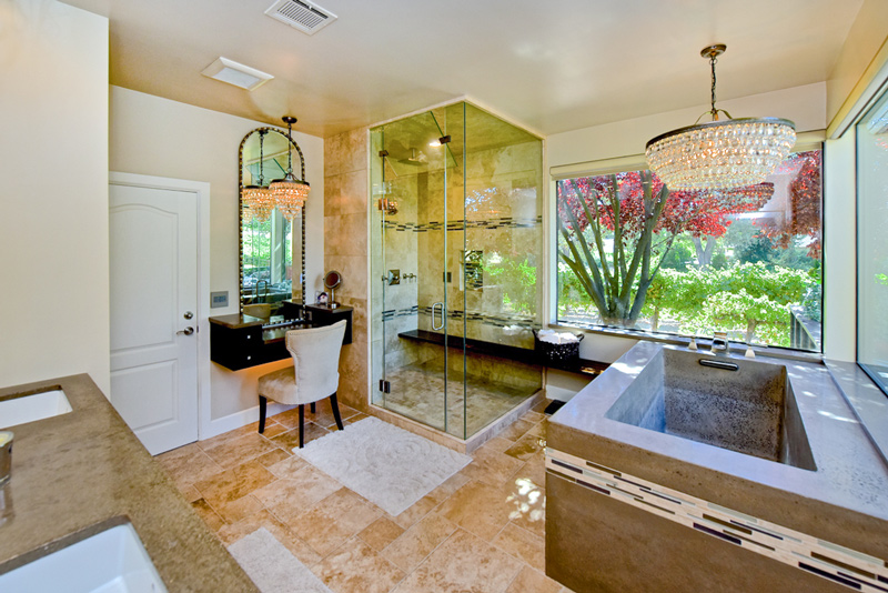 Gorgeous tile and stone bathroom with a shower, tub, vanity, and chandelier.