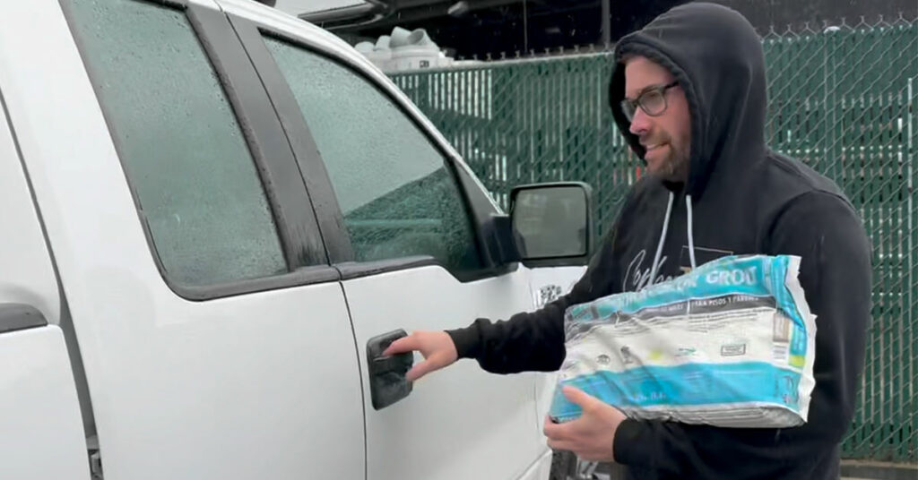 Adam Copher, Owner, places a bag of grout in his truck cab on a rainy day.